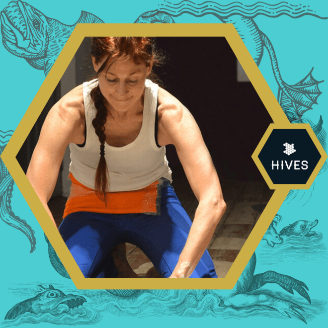 In a golden hexagon, a disabled Indigenous person with light colored skin and redbrown hair kneels, working on something outside of the hexagonal frame. Around the periphery are old stylized drawings of sea monsters on a bluegreen background.